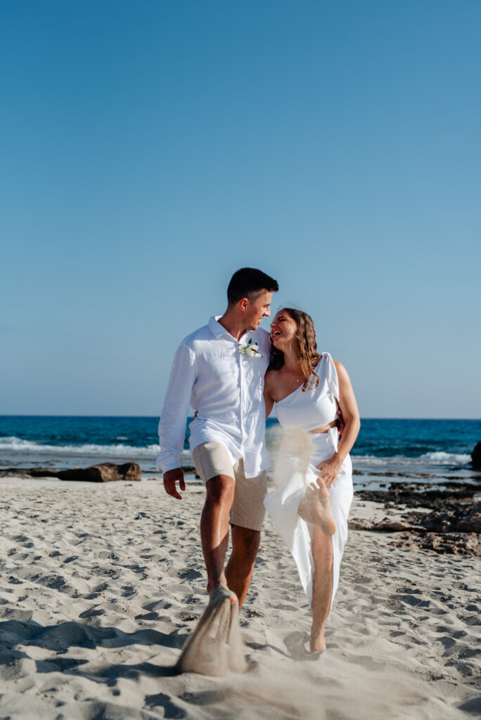 09-09-2024 (164 of 168) Wedding couple having fun, playfully kicking the sand during their beach photoshoot in Ayia Napa, Cyprus, enjoying a carefree moment together
