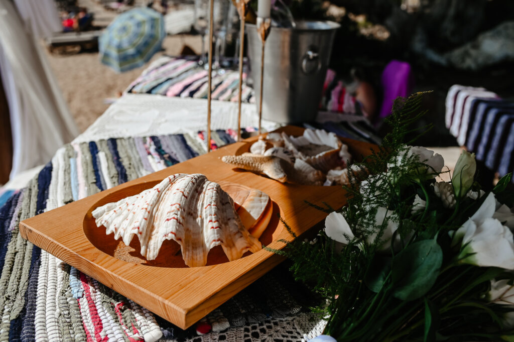 09-09-2024 (2 of 168) (1) Close-up of decorative seashells and a bridal bouquet on a wooden tray at a beach wedding setup in Ammos Kampouri, Ayia Napa