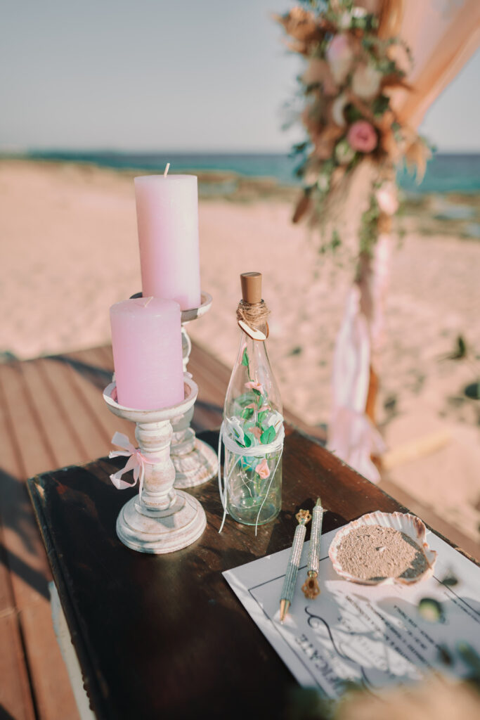 Romantic boho beach decorations at Ayia Thekla beach featured pink candles and bamboo wooden arch
