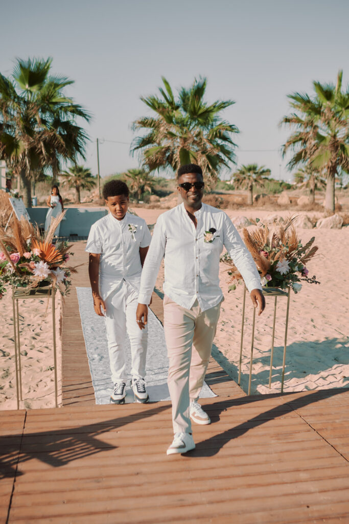 groom walking down the aisle together with his son having fun getting ready for their beach ceremony in Cyprus