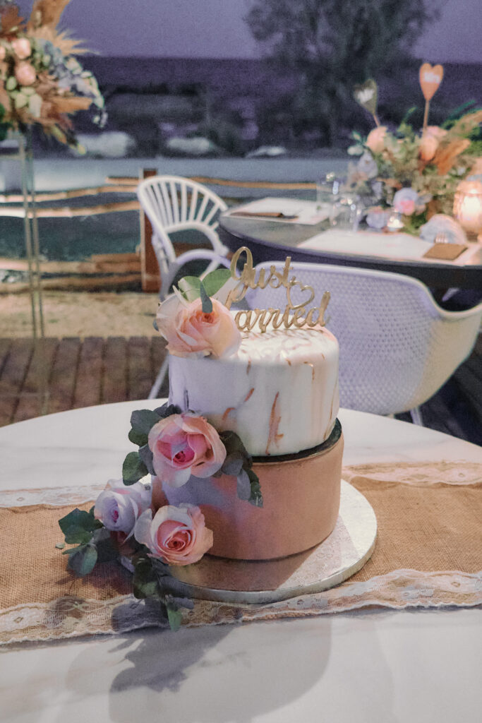 two tier wedding cake with pink roses with beautiful boho decorations and sea backdrop at Montego beach bar in Pernera Cyprus