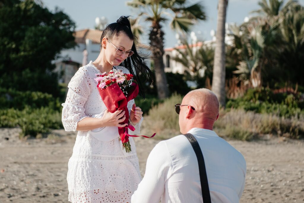 romantic couple dressed up in white enjoying their surprise engagement at the beach near Larnaka Cyprus