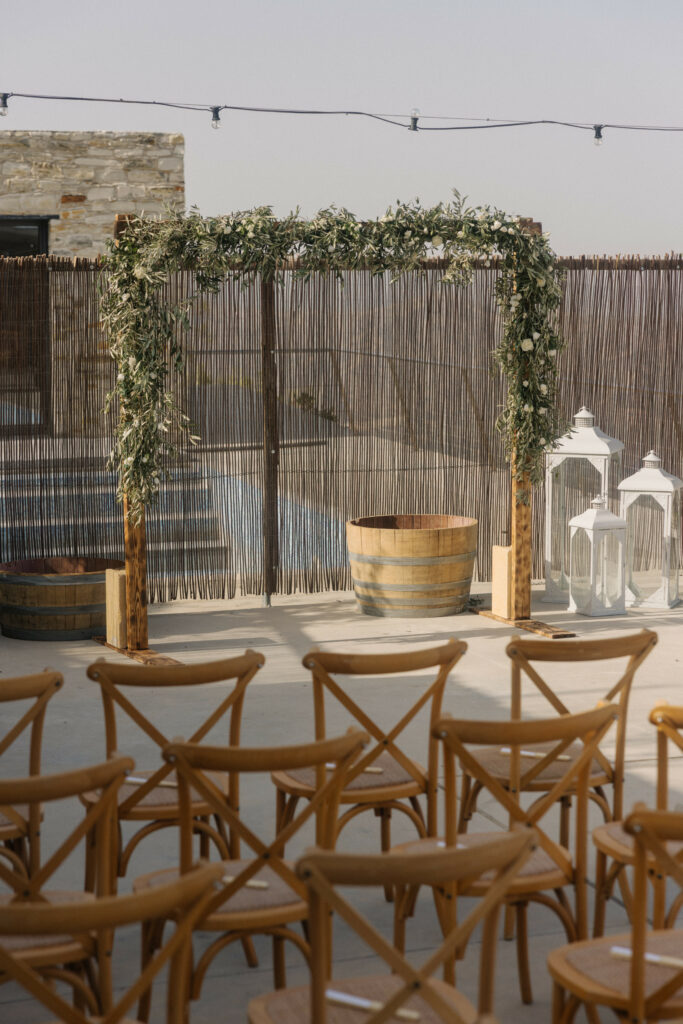 Rustic wedding at Dafermou winery in Cyprus using rectangular wooden ceremony arch with fresh white and green flowers