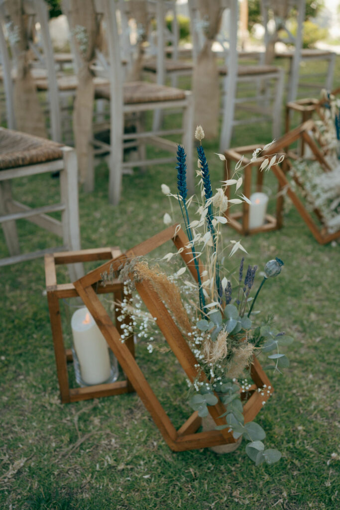 Rustic boho wedding ceremony decor at Larnaca Town Hall with wooden lanterns, dried flowers, and candles on the aisle.