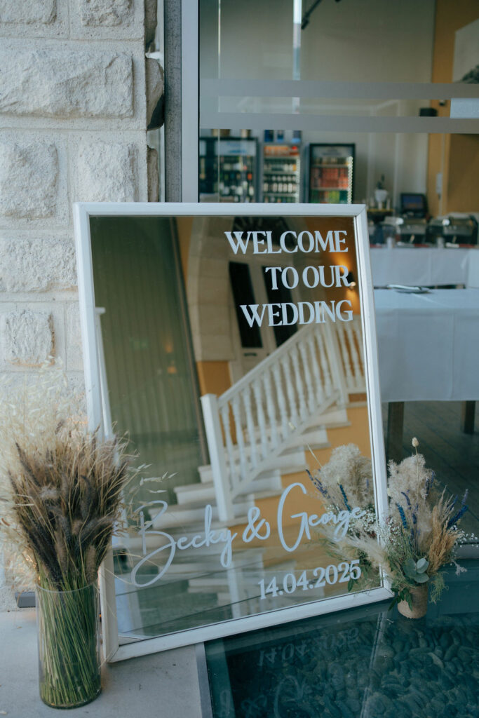 Rustic boho wedding welcome sign with mirror frame and dried flower arrangements at Larnaca Town Hall, Cyprus.
