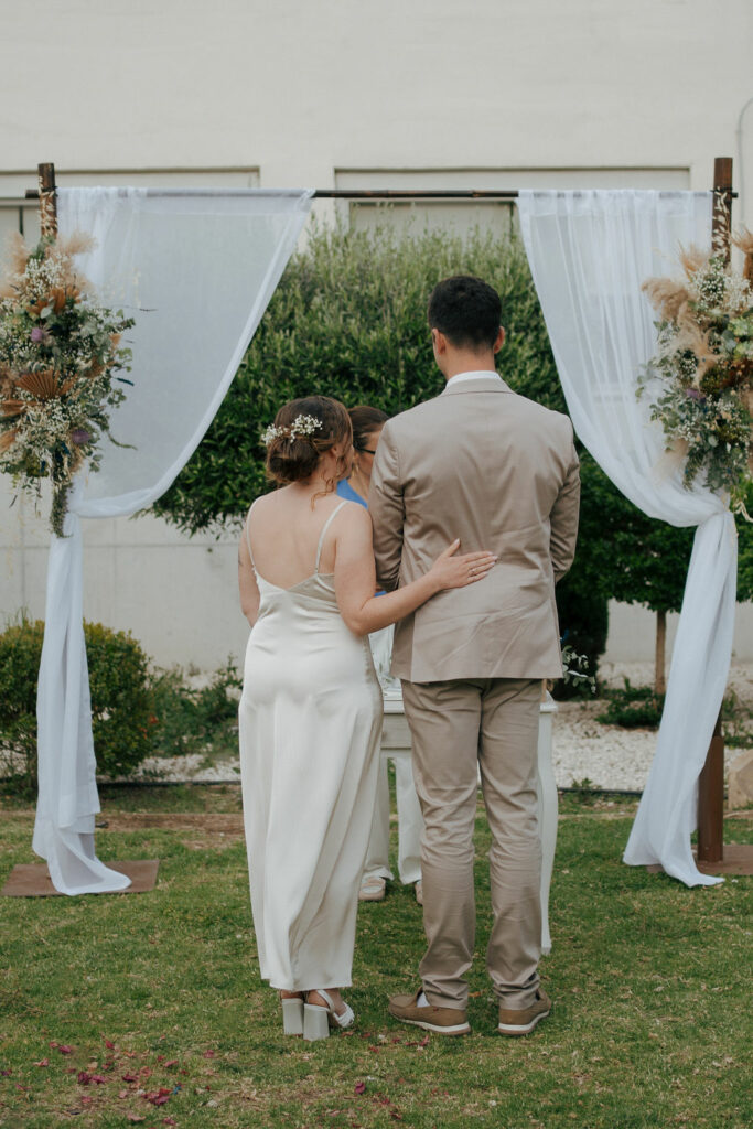 wedding couple standing in front of rustic boho arch with boho decorations during their wedding ceremony in Cyprus