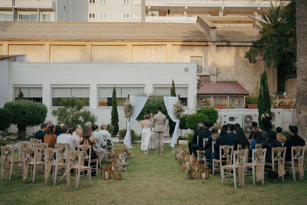 beautiful wedding ceremony at Larnaca town hall with boho set up and couple standing in front of rustic ceremony arch