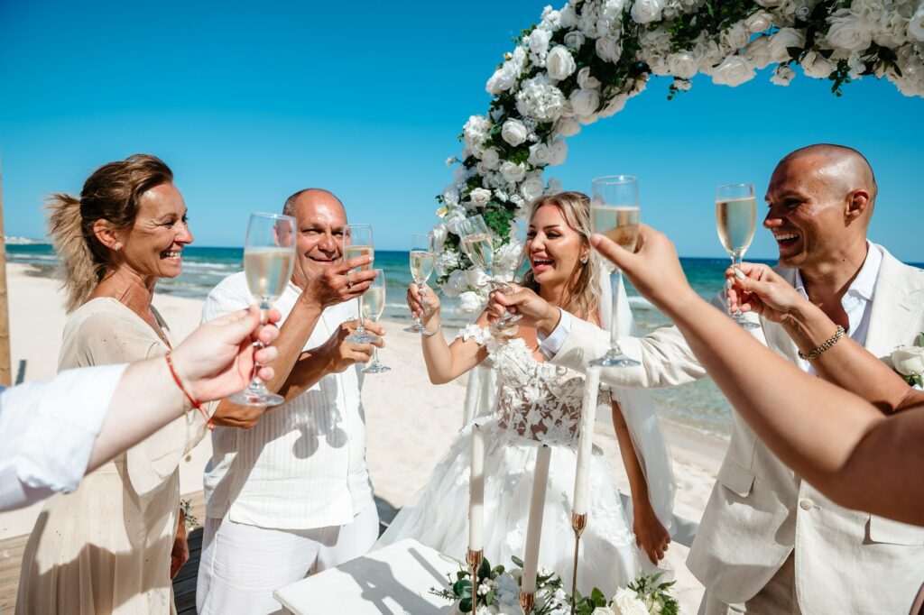 Bride and groom celebrating with family and drinking champagne at Sirens Beach wedding in Cyprus