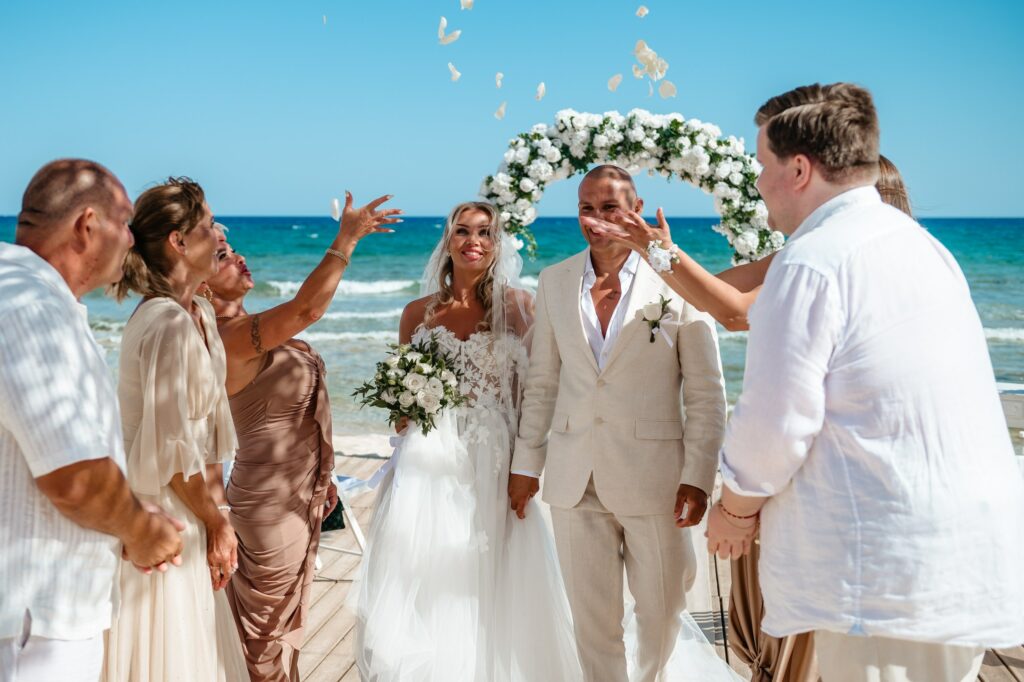 family throwing rose petals at bride and groom at Sirens beach wedding venue