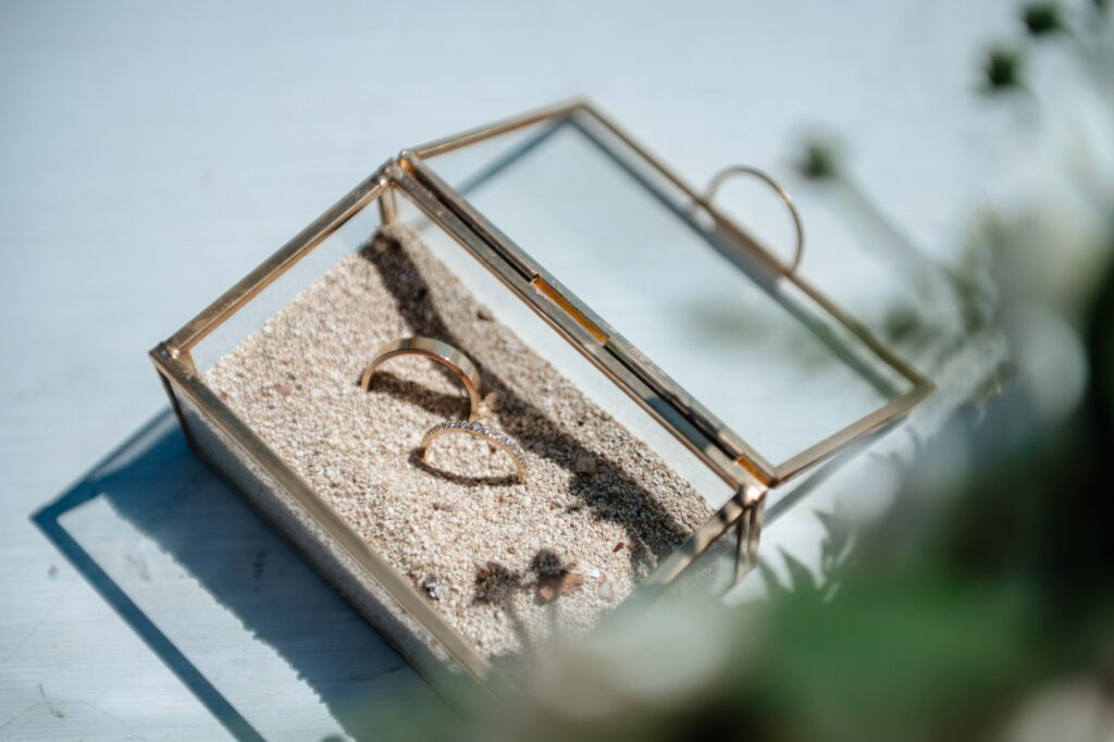 detailed photography of wedding rings in a glass box filled up with sand