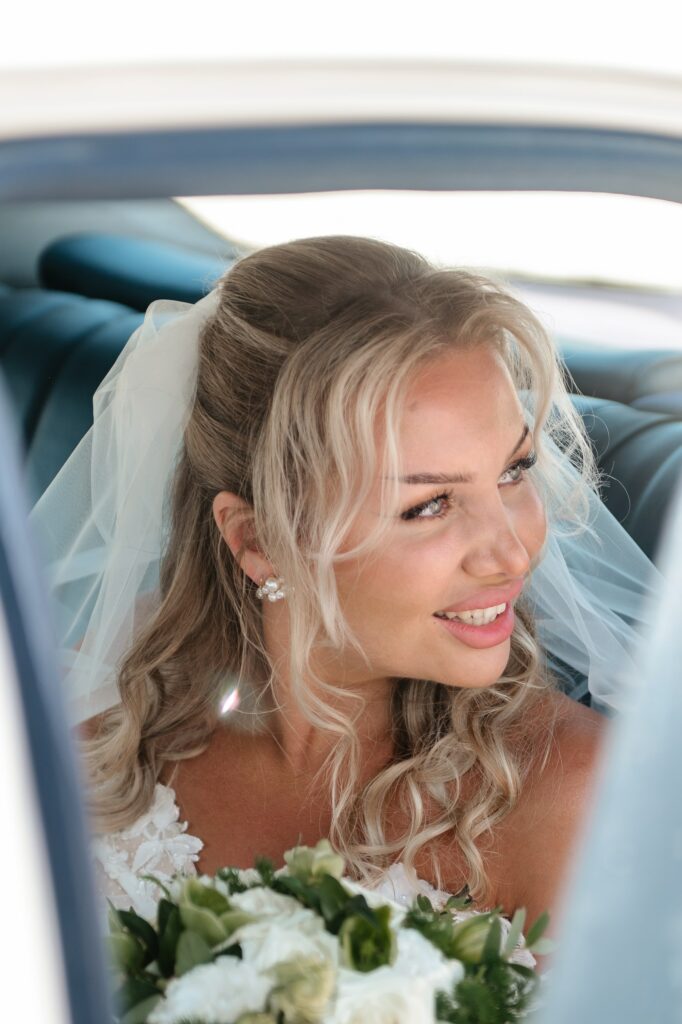 Bride in limousine holding white and green wedding bouquet
