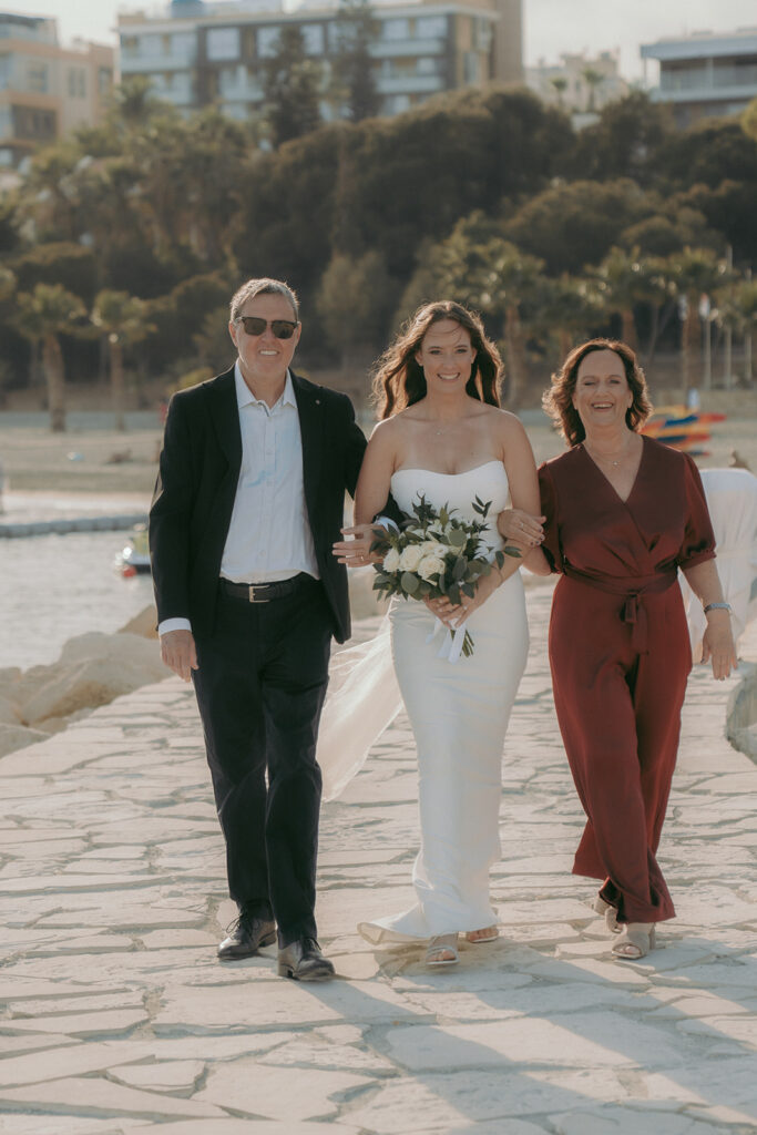 Bride and her parent walking towards the ceremony at the pier in Limassol, Cyprus