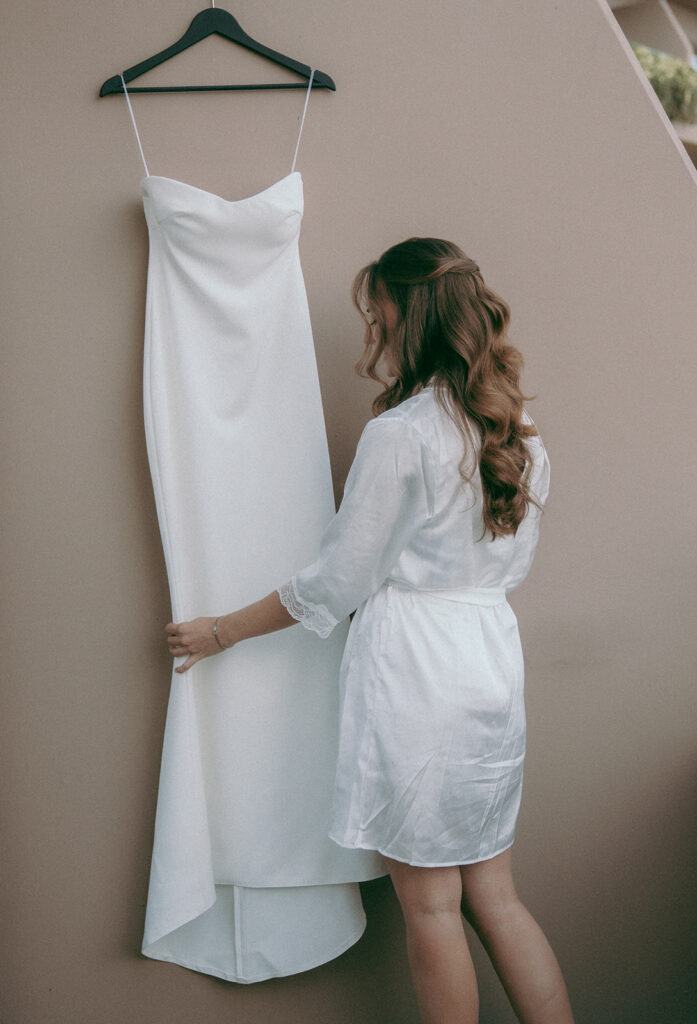 bride checking her wedding dress while getting ready for the ceremony wearing white robe