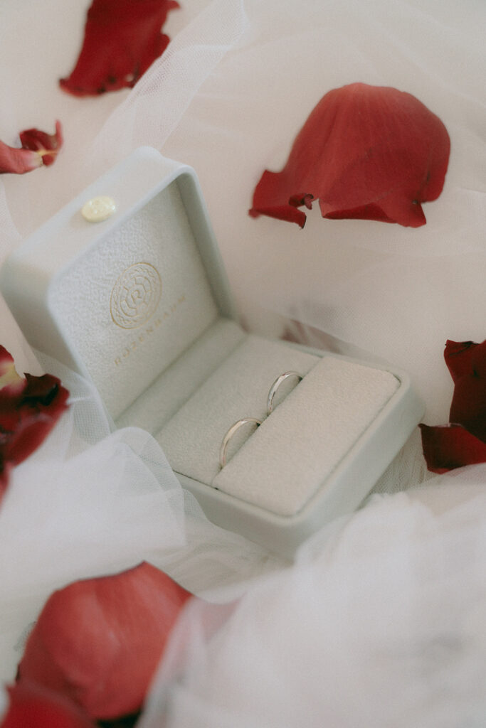 detailed photography of wedding rings with red roses petals