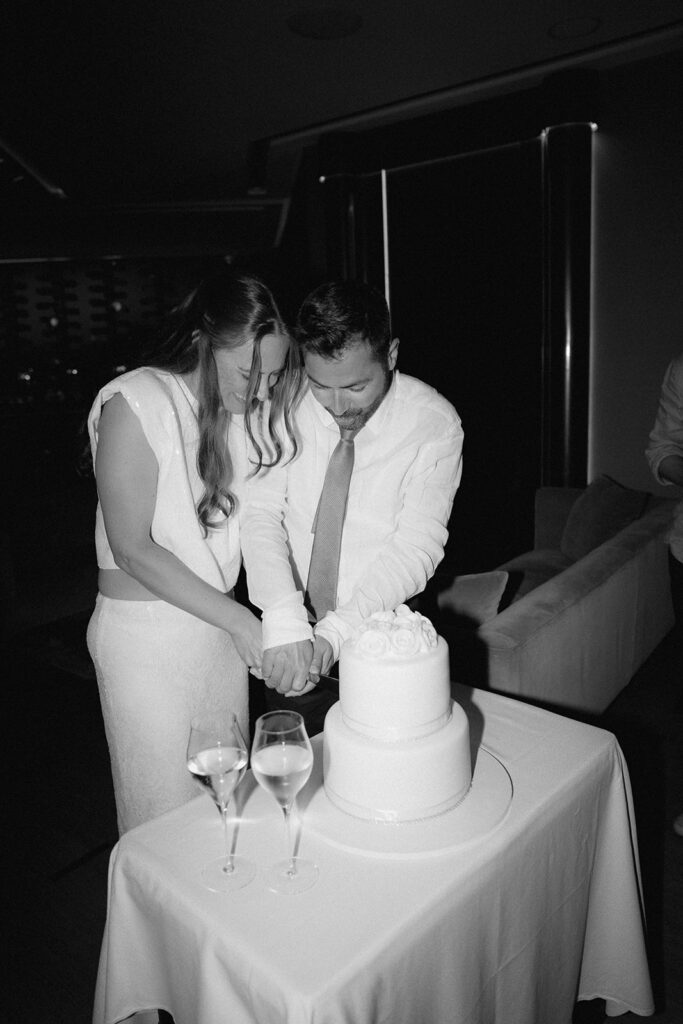 Black and white photo of bride and groom cutting their white wedding cake in Cyprus
