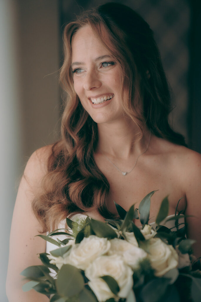 portrait of the bride holding her bouquet made from fresh white roses and greenery