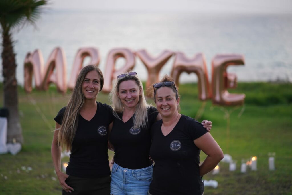 Cyprus wedding planner team in front of Marry Me pink balloons