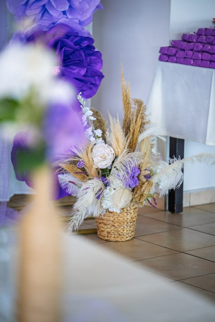 girl's baptism decor Cyprus boho event decor featuring purple and white flowers, pampas grass and rustic table centerpiece