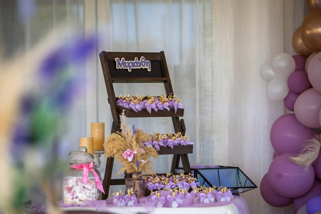 purple themed christening decor Custom made decoration rentals for a girl's baptism in Cyprus featuring a wooden ladder display with lavender favors, pampas grass arrangements, and a purple and gold balloon arch.