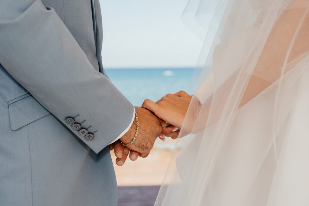 Symbolic beach wedding ceremony in Ayia Napa and Protaras with bride and groom holding hands by the sea, romantic destination wedding in Cyprus planned by professional wedding planner at luxury seaside venue.