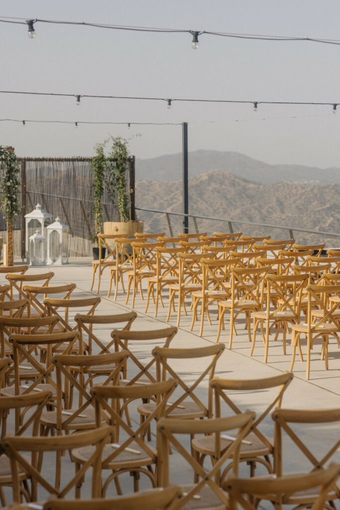 Rustic wedding ceremony decor rentals at Dafermou winery in Cyprus featuring wooden crossback chair rentals and fresh floral arch