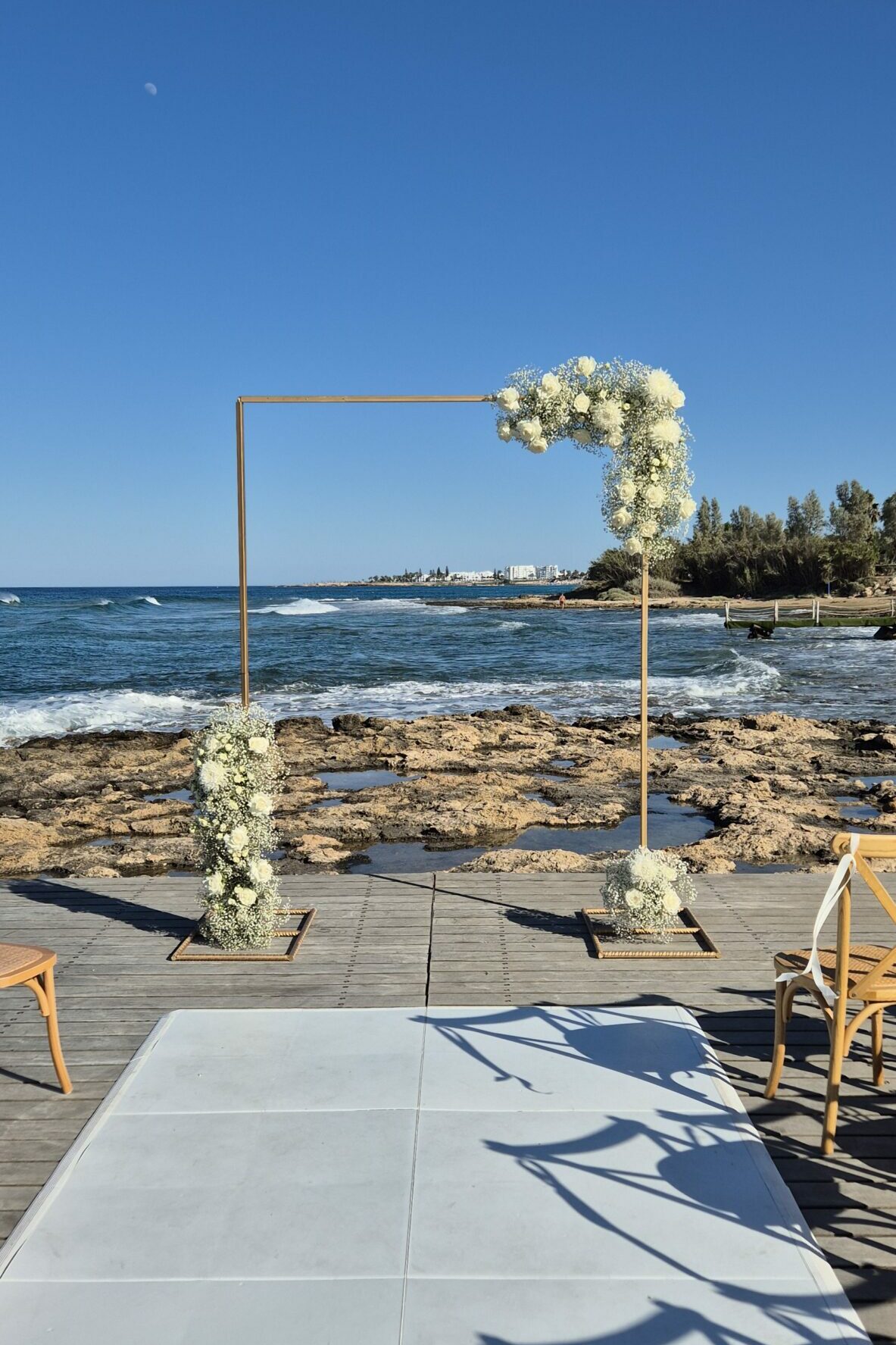 wedding ceremony set up at Poseidon wedding venue in Protaras featuring gold arch with fresh white roses and white aisle