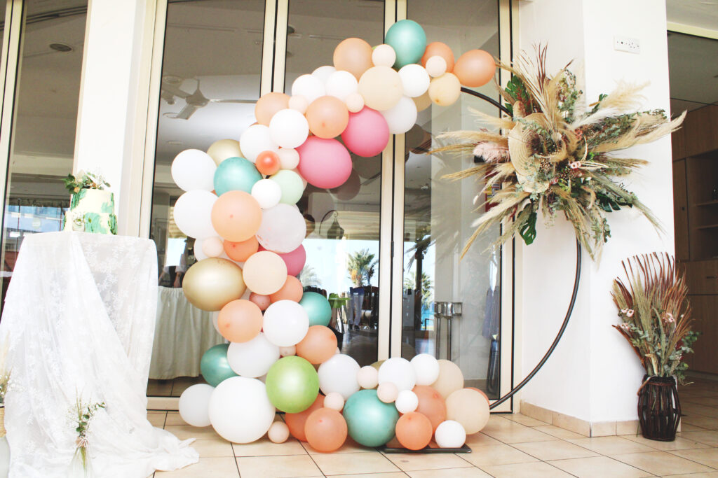 Bespoke organic balloon arch in lavender, gold, and pink featuring an integrated purple tulle backdrop. This custom-made installation includes oversized handcrafted paper flowers and dried pampas grass, perfect for a luxury girl’s christening or fairytale-themed party.