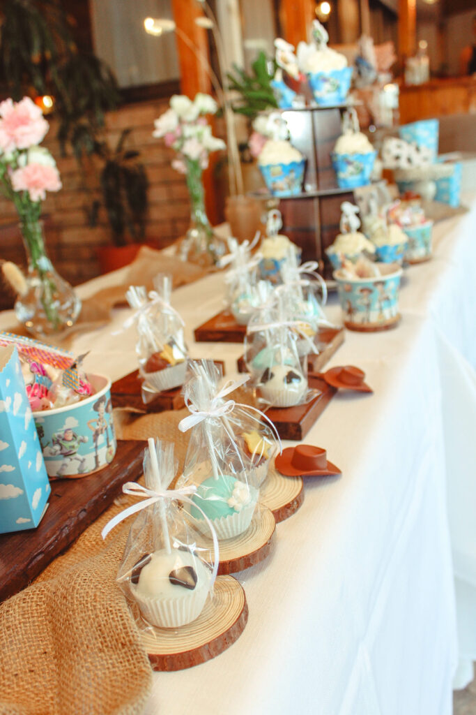 Bespoke Toy Story themed dessert table for a child's birthday, featuring a rustic wooden crate display. The setup includes custom Buzz Lightyear and Woody cake pops, themed sugar cookies, and 'Alien' marshmallow treats, all styled with miniature Toy Story character figures and personalized party favors in Cyprus.