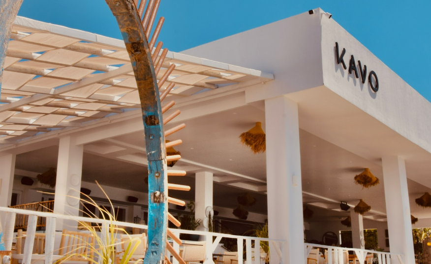 A dreamy beach wedding reception venue in Cyprus, featuring elegant seating with cushions, small tables, and a stunning view of the turquoise Mediterranean Sea and sandy beach, providing a beautiful backdrop for a destination wedding celebration.