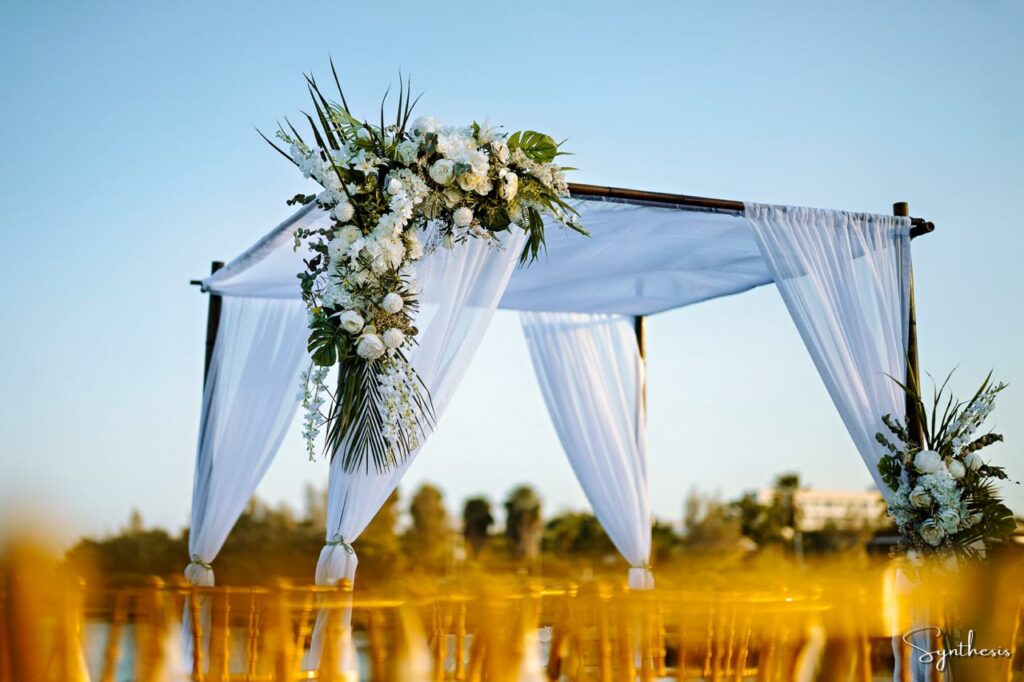 Wedding ceremony gazebo with fresh green and white flowers and gold chairs as a part of decoration rentals in Cyprus