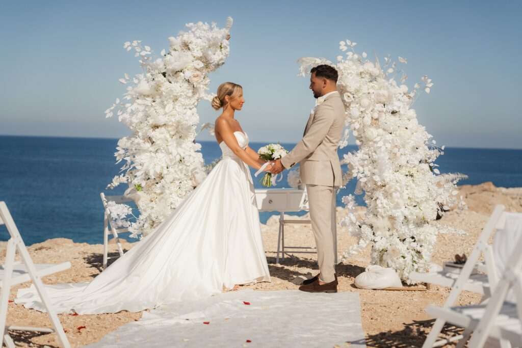 Cyprus wedding ceremony at Coralli Blue Lagoon featuring luxury white wedding decor rentals and a bride and groom
