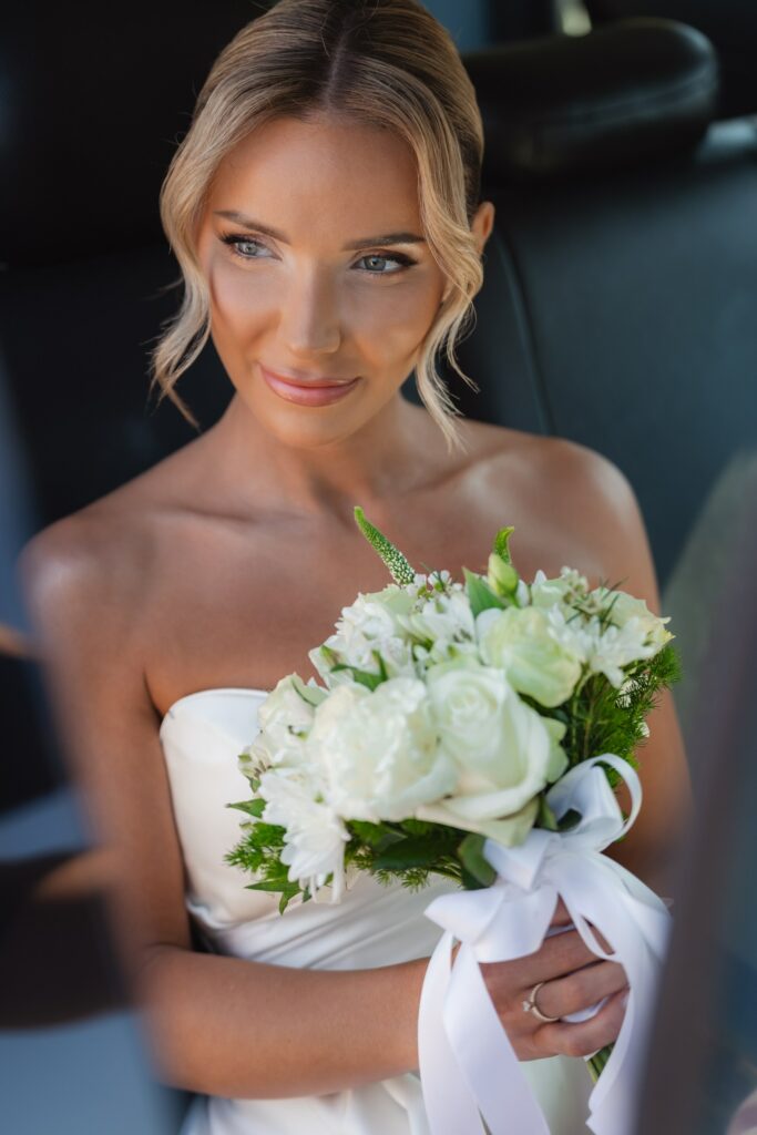 Cyprus wedding photographer bride sitting in the wedding car holding her white floral wedding bouquet